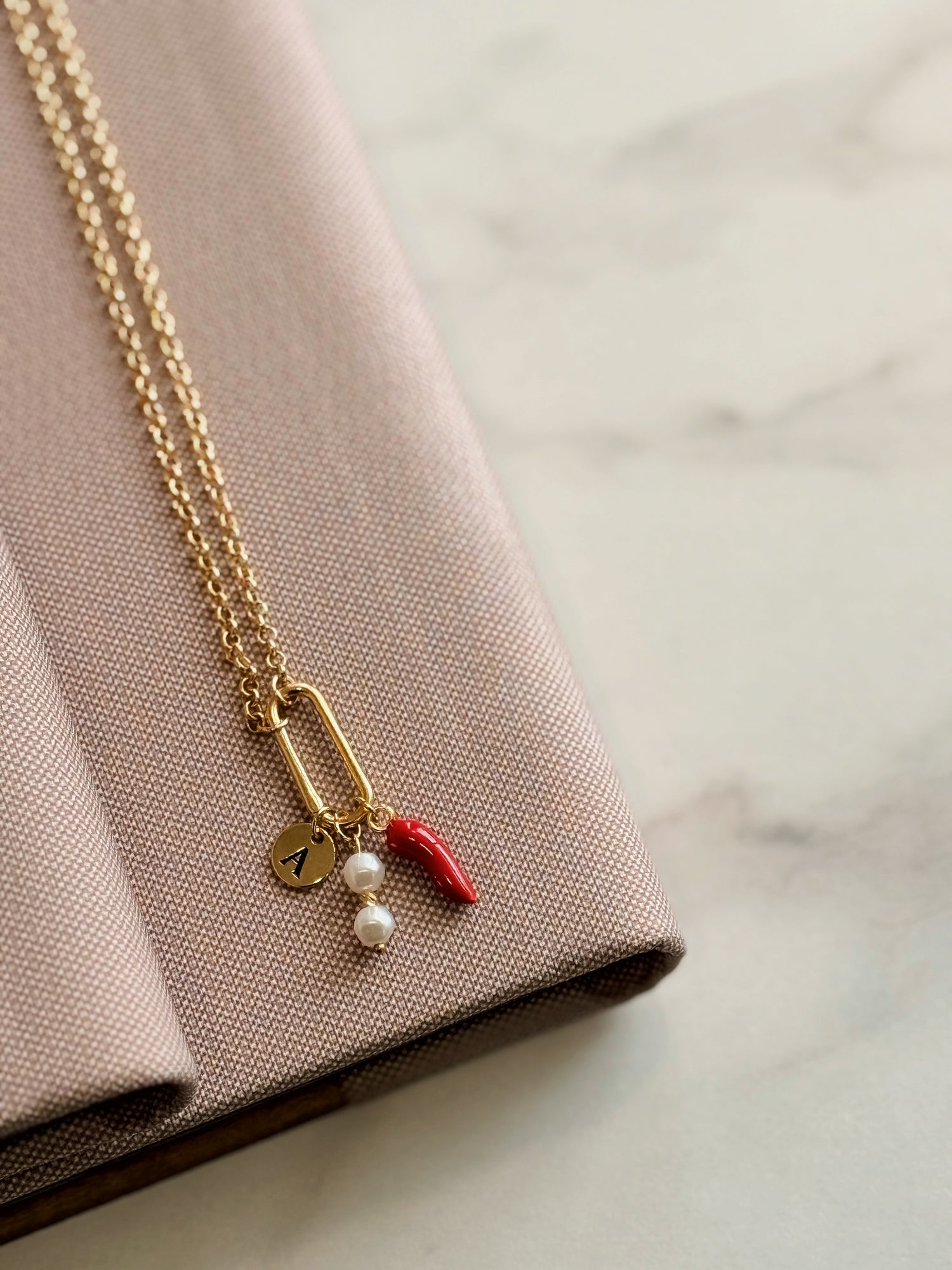 Aura Charm – Edelstahlkette mit Buchstabenanhänger, Süßwasserperle & Paprika-Element